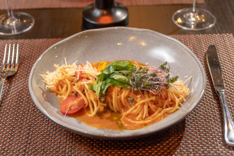 Spaghetti All Arrabbiata: Clásica pasta en salsa de tomate ligeramente picante, terminada con queso parmesano y un toque de albahaca.