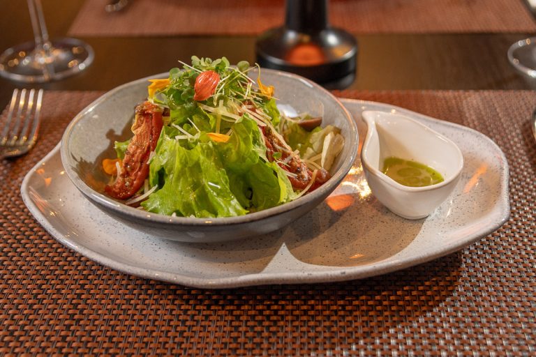 Ensalada Casera: Mix de hojas, panceta crocante, tomate confitado, aceitunas negras, queso rallado y aderezo cítrico.
