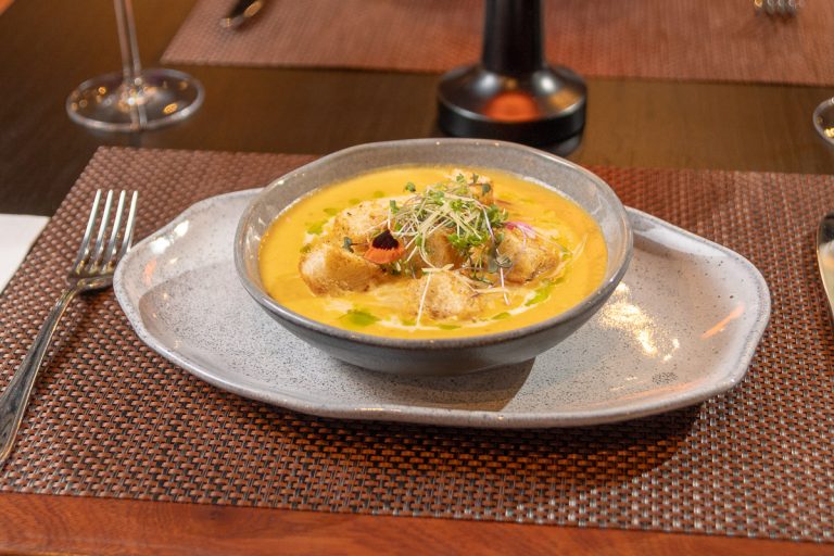 Sopa de Calabaza y Leche de Coco: Suave crema de calabaza, con queso cremoso, jengibre y leche de coco, acompañada de tostones de pan de campo.